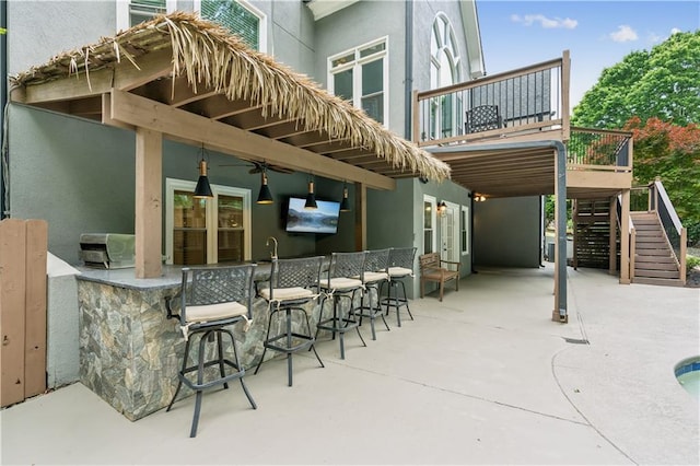 view of patio / terrace featuring a ceiling fan, stairs, and outdoor wet bar