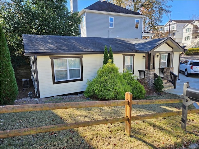 view of front of house with cooling unit, covered porch, and a front yard