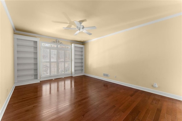 empty room featuring ceiling fan, built in features, crown molding, and dark wood-type flooring