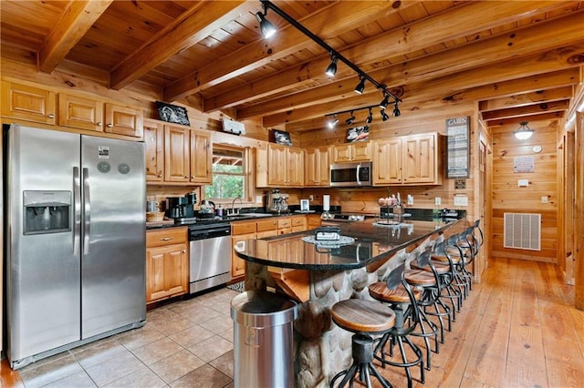 kitchen with beamed ceiling, light hardwood / wood-style floors, a breakfast bar, wood ceiling, and appliances with stainless steel finishes