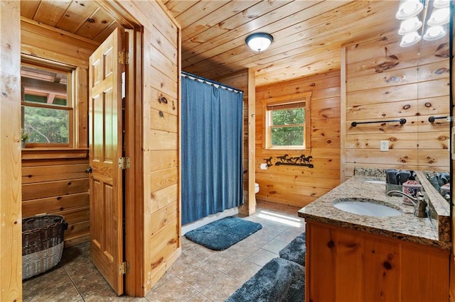 bathroom with tile patterned floors, wood walls, vanity, and wooden ceiling