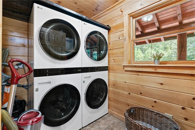 laundry area with wooden walls, washer and dryer, light tile patterned floors, wooden ceiling, and stacked washer and clothes dryer