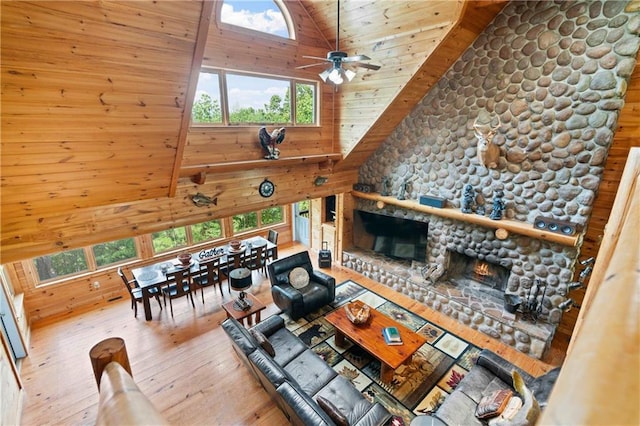 living room featuring wood ceiling, ceiling fan, wooden walls, light hardwood / wood-style flooring, and a fireplace