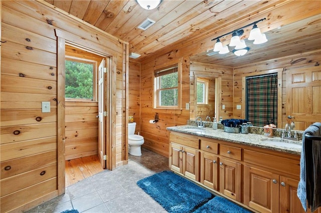 bathroom featuring wood walls, vanity, a healthy amount of sunlight, and tile patterned floors