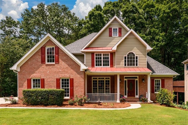 view of front facade with brick siding, a porch, a front lawn, and roof with shingles