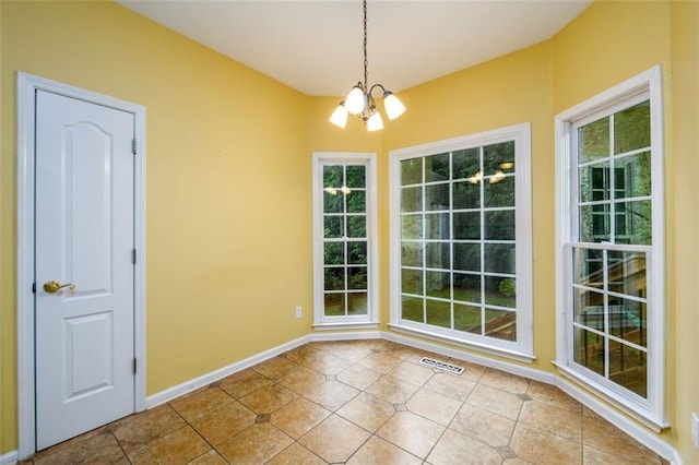 unfurnished dining area featuring a chandelier, healthy amount of natural light, tile patterned floors, and baseboards
