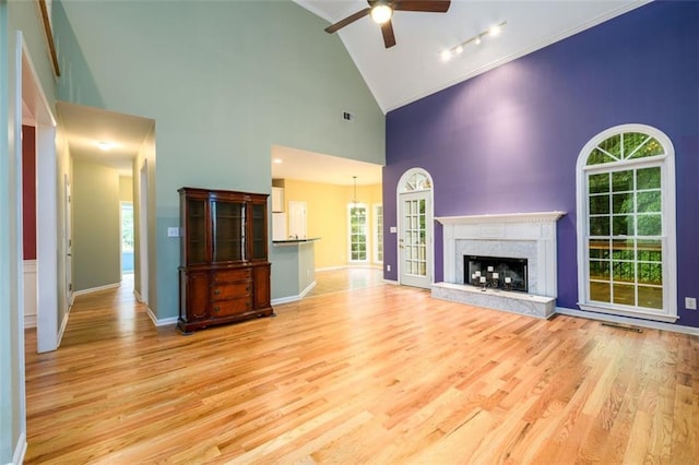 unfurnished living room featuring ceiling fan, high vaulted ceiling, light wood-style floors, and plenty of natural light