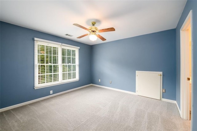 carpeted empty room featuring a ceiling fan and baseboards