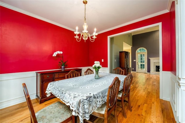 dining area featuring a chandelier, wood finished floors, ornamental molding, and a fireplace