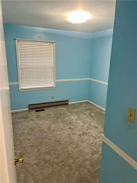 carpeted spare room featuring a baseboard heating unit