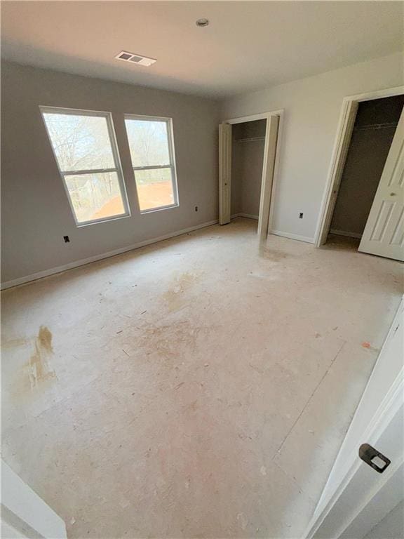 unfurnished bedroom with visible vents, two closets, and baseboards