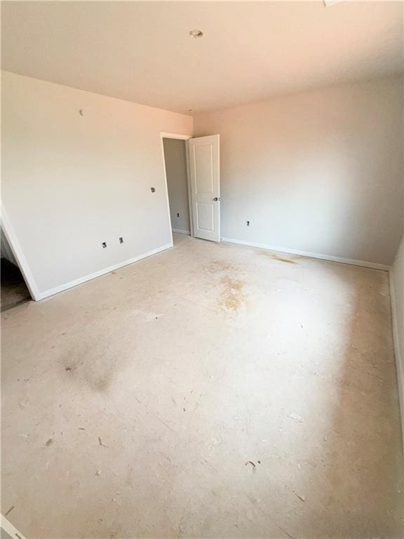 empty room featuring concrete floors and baseboards