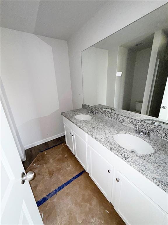 bathroom with a sink, toilet, and double vanity