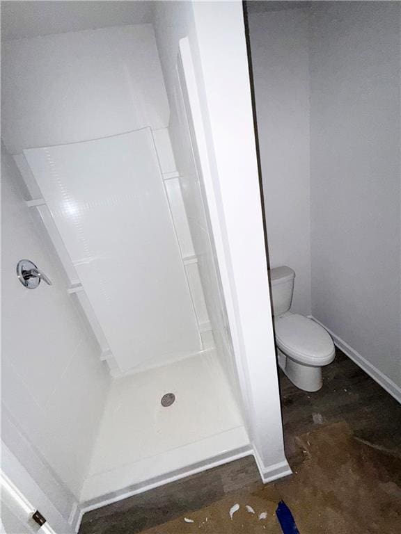 bathroom featuring baseboards, toilet, and a stall shower