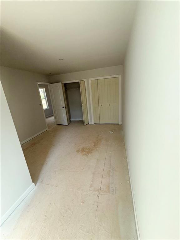 unfurnished bedroom featuring two closets and baseboards