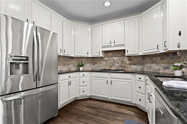 kitchen featuring dark wood-type flooring, decorative backsplash, stainless steel appliances, white cabinetry, and a sink