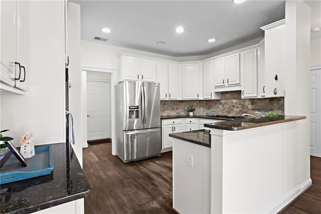 kitchen featuring dark wood-type flooring, stainless steel appliances, a peninsula, white cabinets, and decorative backsplash