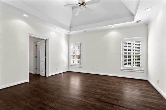 spare room featuring visible vents, a ceiling fan, wood finished floors, baseboards, and a raised ceiling