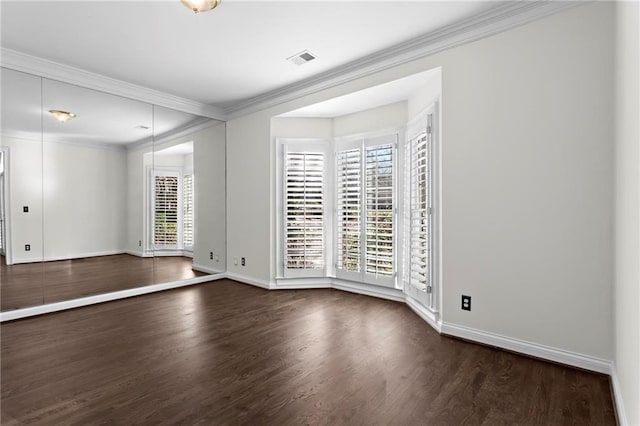 spare room with visible vents, crown molding, dark wood-type flooring, and baseboards