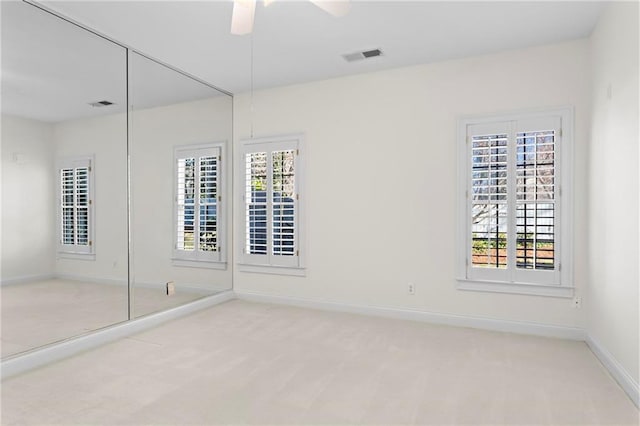 unfurnished bedroom featuring carpet flooring, multiple windows, baseboards, and visible vents