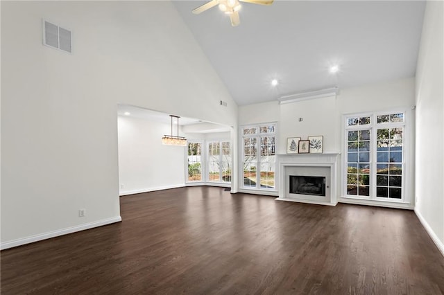 unfurnished living room with visible vents, baseboards, dark wood finished floors, a fireplace with flush hearth, and high vaulted ceiling