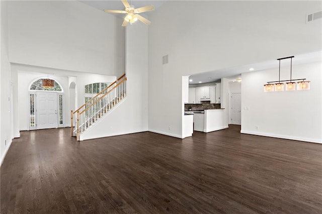 unfurnished living room with dark wood finished floors, visible vents, stairs, and baseboards