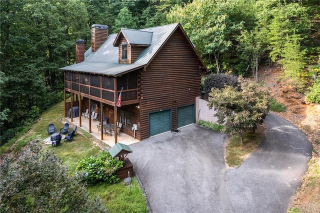 105 Ranch Mountain Ct, Dahlonega, GA 30533 - view of front facade with asphalt driveway, a chimney, log exterior, a view of trees, and central AC