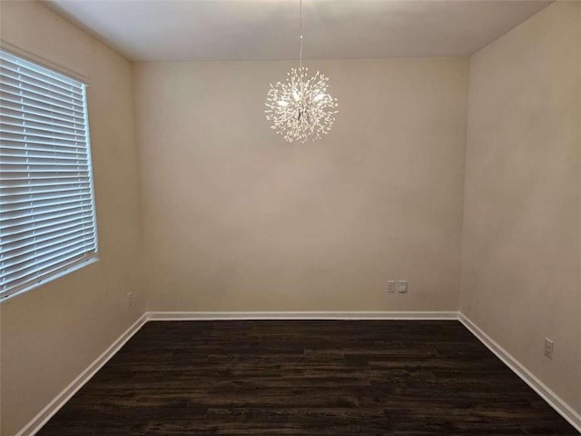 spare room with a chandelier and dark hardwood / wood-style flooring