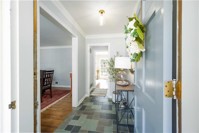 hallway featuring dark wood-style floors, ornamental molding, visible vents, and baseboards