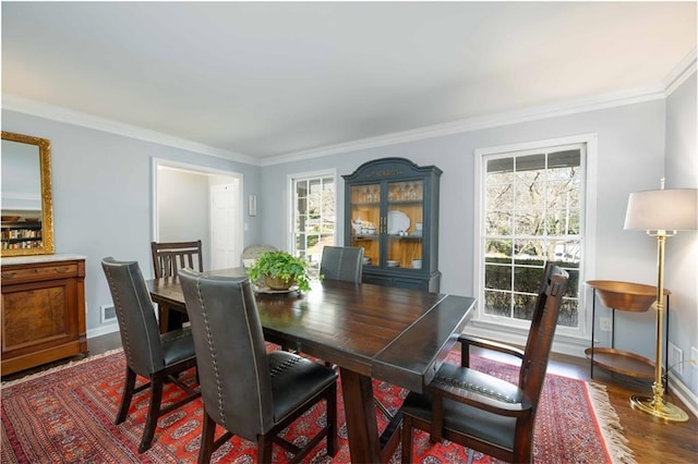 dining room featuring crown molding, baseboards, and wood finished floors