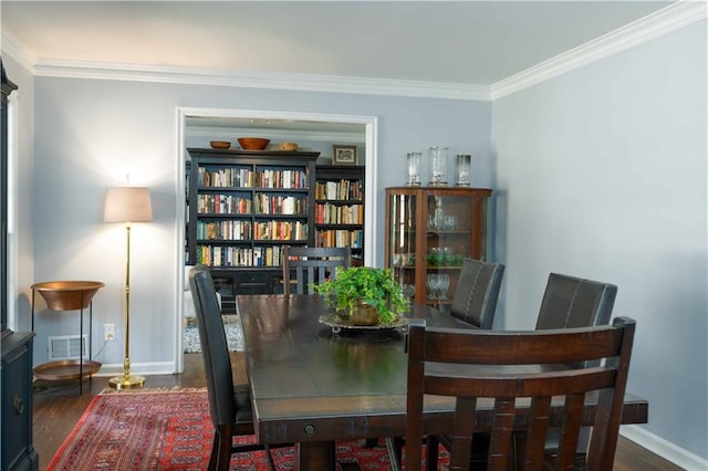 dining room featuring baseboards, visible vents, ornamental molding, and wood finished floors