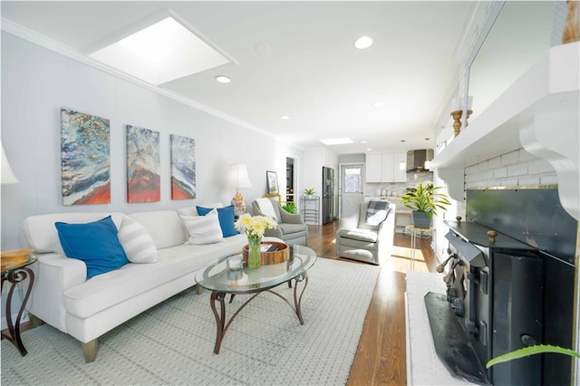 living room featuring a skylight, crown molding, recessed lighting, and wood finished floors