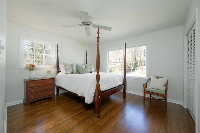 bedroom with a closet, dark wood-style flooring, baseboards, and a ceiling fan