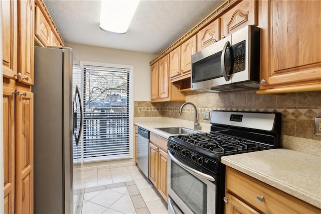 kitchen with sink, stainless steel appliances, a textured ceiling, decorative backsplash, and light tile patterned floors