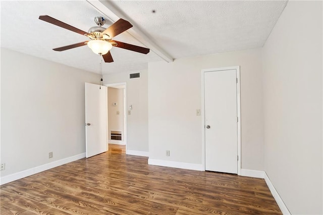 spare room featuring ceiling fan, beam ceiling, dark hardwood / wood-style flooring, and a textured ceiling