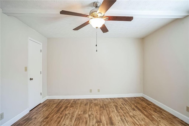 empty room featuring ceiling fan, beamed ceiling, and hardwood / wood-style flooring