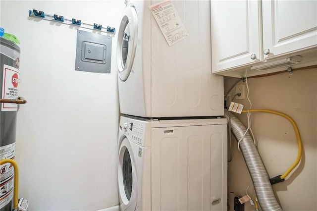 washroom featuring cabinets, stacked washer / drying machine, and water heater