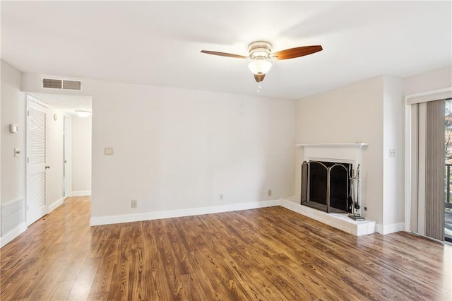 unfurnished living room with ceiling fan, wood-type flooring, and a brick fireplace