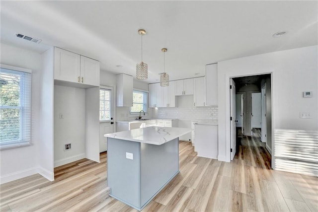 2502 Tupelo St SE, Atlanta, GA 30317 - kitchen with white cabinetry, a center island, light wood-style flooring, and decorative backsplash
