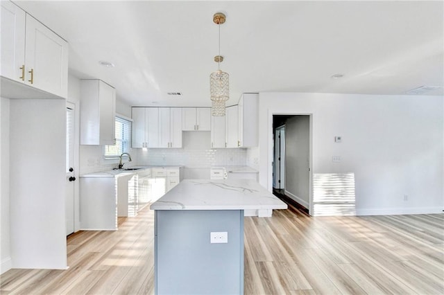 2502 Tupelo St SE, Atlanta, GA 30317 - kitchen with light wood-type flooring, light stone countertops, tasteful backsplash, white cabinets, and a sink