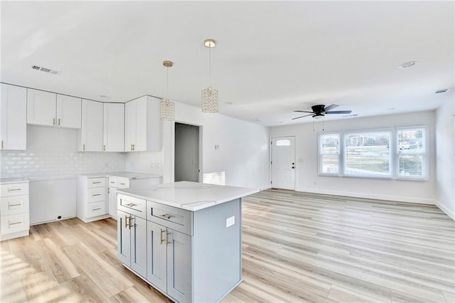 2502 Tupelo St SE, Atlanta, GA 30317 - kitchen featuring light wood-style floors, ceiling fan, pendant lighting, white cabinetry, and backsplash