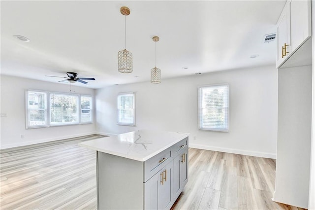 2502 Tupelo St SE, Atlanta, GA 30317 - kitchen with light wood finished floors, a kitchen island, gray cabinets, pendant lighting, and ceiling fan