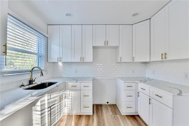 2502 Tupelo St SE, Atlanta, GA 30317 - kitchen featuring a sink, light stone countertops, white cabinetry, light wood-type flooring, and decorative backsplash