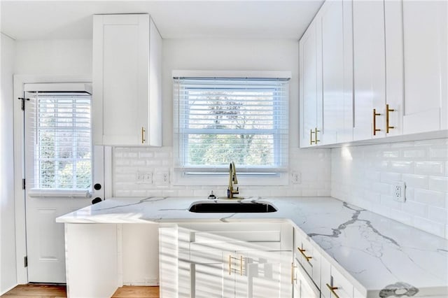 2502 Tupelo St SE, Atlanta, GA 30317 - kitchen featuring a sink, light stone counters, white cabinets, and backsplash