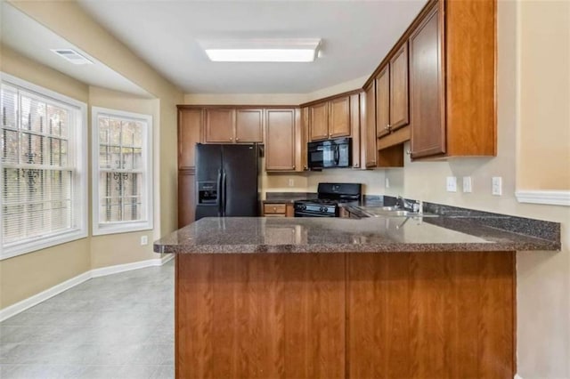 kitchen featuring dark stone counters, kitchen peninsula, sink, and black appliances