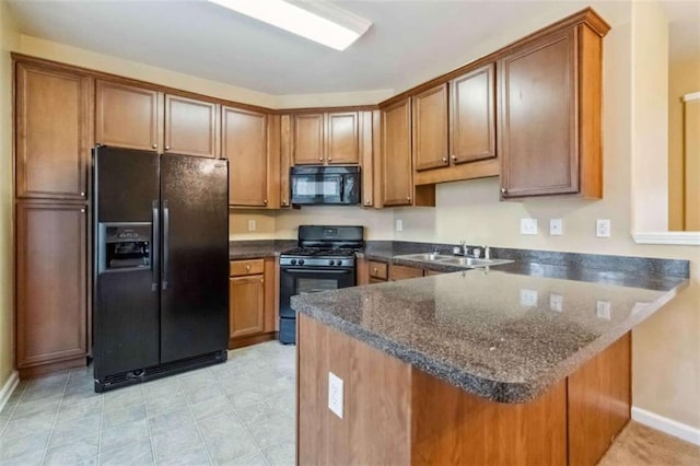 kitchen featuring black appliances, kitchen peninsula, sink, and dark stone counters