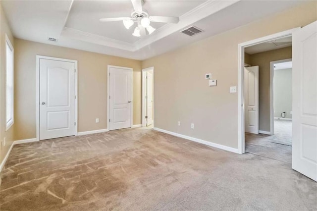 unfurnished bedroom with ceiling fan, a raised ceiling, and carpet floors