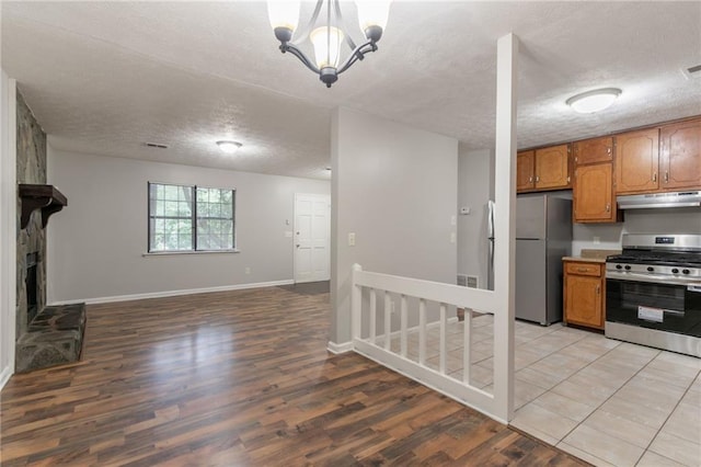 5218 Tina Ct, Stone Mountain, GA 30083 - kitchen featuring stainless steel appliances, under cabinet range hood, a textured ceiling, open floor plan, and brown cabinets