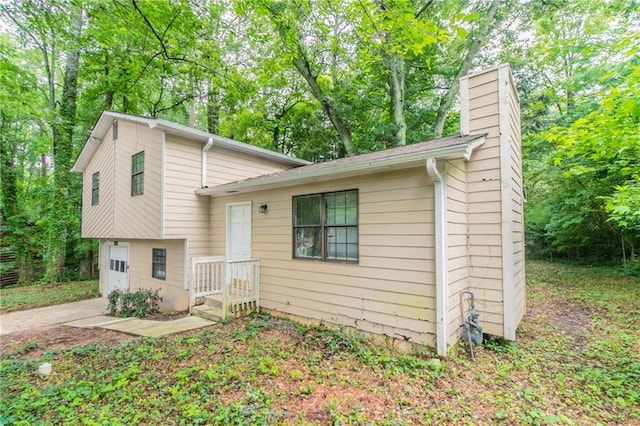 5218 Tina Ct, Stone Mountain, GA 30083 - tri-level home featuring a chimney, an attached garage, concrete driveway, and view of wooded area
