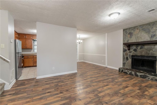5218 Tina Ct, Stone Mountain, GA 30083 - unfurnished living room with wood finished floors, a textured ceiling, a fireplace, baseboards, and a chandelier